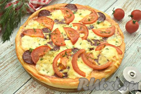 Готовую мягкую, ароматную выпечку достаём из духовки. Аналогично из второй части теста и оставшейся начинки формируем вторую пиццу и выпекаем в духовке. Пицца с сочной начинкой из моцареллы, колбасы и помидоров получилась очень вкусной. По желанию, посыпаем её мелко нарезанным укропом. Нарезаем пиццу на кусочки и в горячем виде подаём к столу. Угощайтесь!