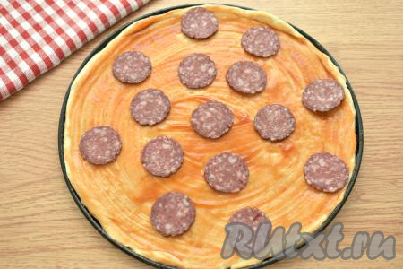 Колбасу нарезаем на тонкие кружки. Половину нарезанной колбасы выкладываем на тесто.