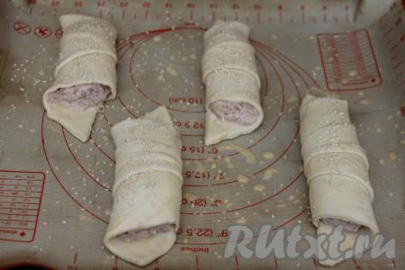 Смазать круассаны взбитым желтком, затем присыпать кунжутом.