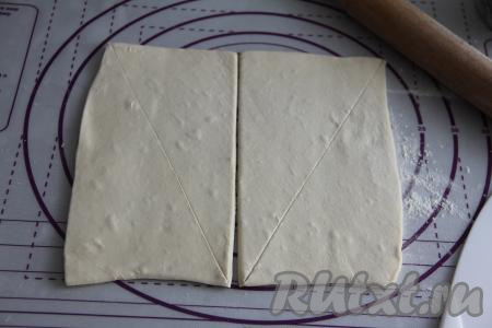 Слегка раскатать размороженный пласт слоёного теста на присыпанной мукой поверхности. Получившийся пласт теста разрезать на два одинаковых прямоугольника. Каждый прямоугольник разрезать по диагонали на 2 части.