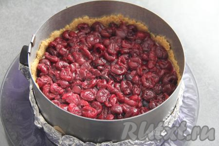 Затем поверх застывшей творожной массы равномерно выложить вишню, смешанную с сахаром.