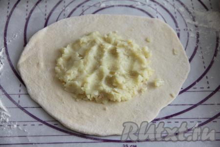 Тесто обмять и разделить на 6 равных частей. Начинку тоже зрительно разделить на 6 частей. Каждую часть теста раскатать на присыпанной мукой поверхности в достаточно тонкую лепёшку. В центр лепёшки выложить одну часть картофельно-луковой начинки.