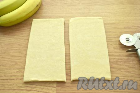 Выкладываем на стол, присыпанный мукой, один размороженный пласт слоёного теста, раскатывать его не нужно. Разрезаем этот пласт на 2 равных прямоугольника.