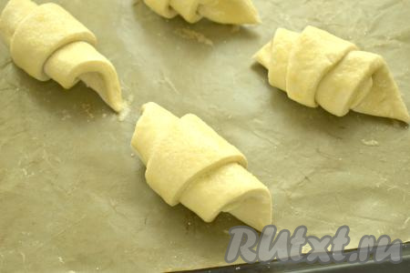 На противень, застеленный ковриком (или бумагой) для выпечки, выкладываем сформированные слойки с начинкой из банана так, чтобы "хвостик" был снизу. Выкладывать нужно на расстоянии друг от друга, так как рулетики&nbsp; увеличатся в процессе выпечки. Оставляем заготовки слоек на расстойку минут на 20-25 в тёплом месте. Благодаря расстойке слойки из дрожжевого теста получатся воздушными и очень аппетитными. По прошествии 20-25 минут в небольшой ёмкости вилкой взбиваем яйцо. Смазываем поверхность слоек взбитым яйцом. Каждую слойку присыпаем сверху 0,5 чайной ложки сахара и отправляем в разогретую до 200 градусов духовку.