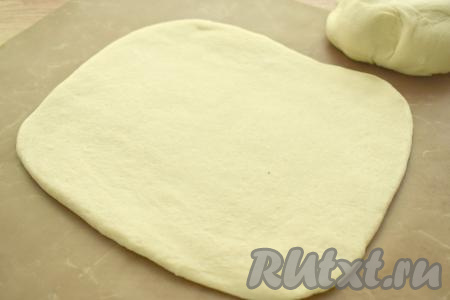Поднявшееся тесто обминаем, делим на 2 части так, чтобы одна часть теста была немного больше. Большую часть теста на присыпанной мукой поверхности раскатываем в овальный (или круглый) пласт толщиной примерно 7-8 миллиметров. Раскатанное тесто перекладываем на противень, застеленный ковриком (или пергаментом) для выпечки.
