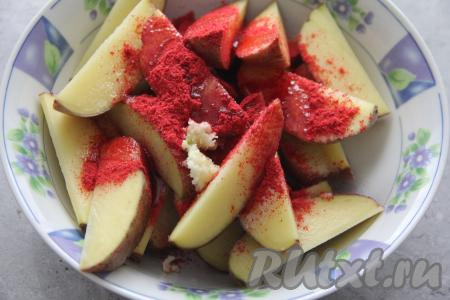 Картошку нарезать на крупные дольки, переложить в объёмную миску, добавить соль, паприку, пропущенный через пресс зубчик чеснока, влить масло.