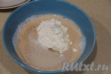 Для начала приготовим опару. Для этого воду, подогретую до 38-40 градусов (выше температуры воды быть не должна), вылить в небольшую ёмкость, всыпать сухие дрожжи и сахар, тщательно перемешать, добавить 1 столовую ложку муки от общей массы, перемешать и оставить на 15 минут.