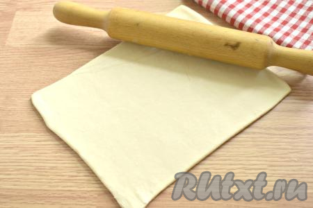 Тесто можно взять и дрожжевое, и бездрожжевое (у меня - дрожжевое). Слоёное тесто размораживаем при комнатной температуре. Стол присыпаем примерно 1 чайной ложкой муки, выкладываем размороженный пласт теста. Раскатываем его в одном направлении, получится прямоугольник, размер которого будет примерно 24 сантиметра на 18 сантиметров.