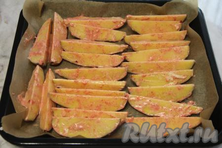 Противень застелить пергаментом (или ковриком для выпечки), затем выложить в один слой дольки картофеля.