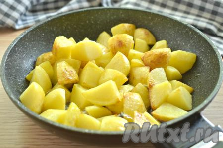 Чтобы во время тушения на сковороде кусочки картофеля не развалились и блюдо не превратилось в кашу, предварительно обжарим картошку в растительном масле. Для этого вливаем на сковороду растительное масло и хорошо его разогреваем. Перекладываем в горячее масло кубики картофеля, делаем огонь достаточно сильным. Обжариваем картошку в течение 6-7 минут (до появления лёгкой румяной корочки со всех сторон). Картошка останется ещё сырой, она только подрумянится. Обжаренную картошку со сковороды на время, пока будем обжаривать морковку с луком и охотничьими колбасками, перекладываем в тарелку.