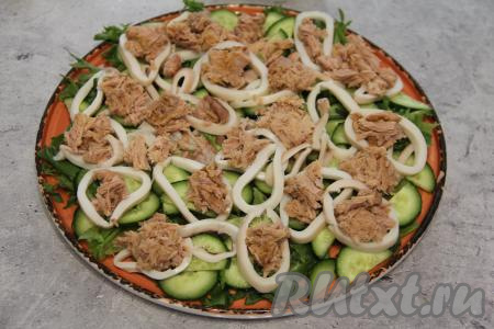 С тунца слить жидкость, затем разложить кусочки тунца на кальмаров.