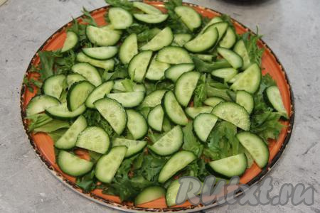 Поверх салата выложить огурец, нарезанный на тонкие полукружочки, посолить.