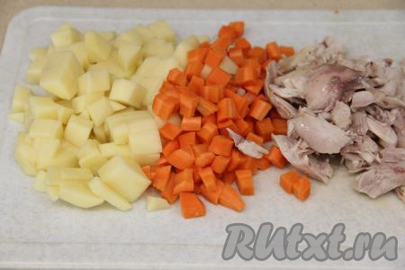 Промыть кусочки курицы, выложить в кастрюлю, влить 2 литра воды и поставить на огонь. После закипания бульона уменьшить огонь, убрать пену и варить куриное мясо минут 30. Затем достать мясо, остудить, отделить его от костей. Картошку и морковь почистить, нарезать на кубики. Бульон, если нужно, процедить, затем снова перелить в кастрюлю, поставить на огонь.