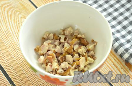 Копчёное мясо курицы отделяем от костей, если они есть. Крабовые палочки полностью размораживаем, снимаем с них плёнку. Яйца варим вкрутую (после закипания воды в течение 10 минут), затем даём им остыть и очищаем. Нарезаем 200 грамм копчёного куриного мяса на маленькие кубики, перекладываем в достаточно глубокую миску.