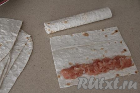 Нарезать лаваш на 6 прямоугольников размером примерно 16 сантиметров на 11 сантиметров. Подготовленный фарш разделить на 6 частей (по количеству трубочек из лаваша, которые мы будем формировать). На прямоугольник из лаваша, отступив от более широкого края примерно 1 сантиметр, выложить одну часть фарша, как на фото.