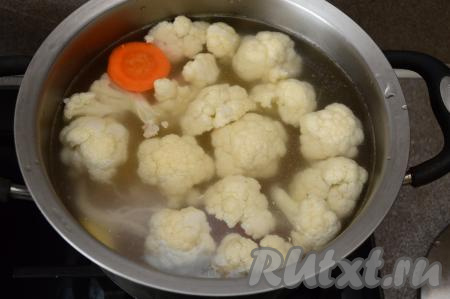 В куриный бульон выложить нарезанные мясо, морковку, цветную капусту и картошку, поставить на огонь.