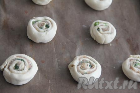 Выложить заготовки слоёных рулетиков срезом вверх на расстоянии друг от друга на противень, застеленный ковриком (или пергаментом) для выпечки.