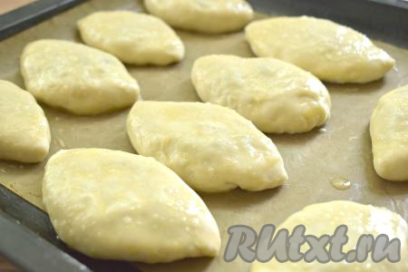 Скрепляем края лепёшки над яично-луковой начинкой, формируя пирожок. Выкладываем пирожок швом вниз на противень, застеленный пергаментом. Один за другим формируем все пирожки, выкладываем их швом вниз на застеленный противень на расстоянии друг от друга. Накрываем наши пирожки полотенцем и оставляем для расстойки на 15 минут. В небольшой ёмкости взбиваем вилкой сырое яйцо. После расстойки смазываем пирожки взбитым яйцом и ставим в духовку, прогретую до 190 градусов.