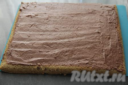Остывший корж перевернуть на пергамент, снять коврик (или пергамент), на котором он выпекался. Затем равномерно смазать бисквит кремом.