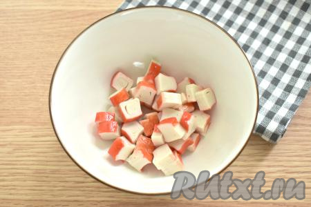 Размороженные крабовые палочки извлекаем из упаковки, нарезаем на кусочки среднего размера, перекладываем в миску.