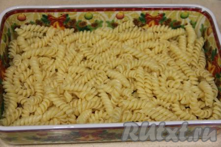 В жаропрочную форму выложить половину отваренных макарон.
