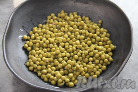 Салат "На траве дрова" выкладывается слоями. На сухарики, смазанные майонезом, достаточно ровным слоем выложить консервированный горошек без жидкости.