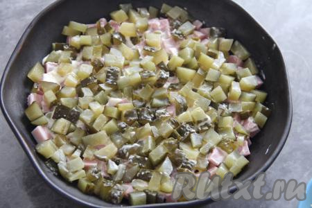 Смазать слой ветчины майонезом. Далее равномерно выложить огурцы, нарезанные на мелкие кубики.