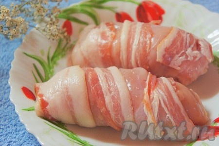 Каждый получившийся куриный рулет с сыром и перцем плотно обернуть тонкой полоской бекона, выложить в форму, застеленную пергаментом, и отправить в предварительно разогретую до 200 градусов духовку на 30 минут.
