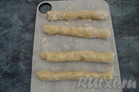 Доску, на которой будете формировать ленивые вареники, присыпать примерно 1 столовой ложкой овсяной муки. Разделить тесто на 4 части. Скатать из каждой части теста колбаску толщиной примерно 2 сантиметра, слегка обваливая каждую колбаску в овсяной муке, которой мы присыпали доску.