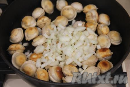 Обжарить пельмени с двух сторон до золотистого цвета на среднем огне. Затем добавить нарезанный лук, сразу перемешать.