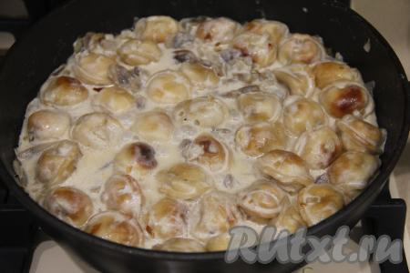 После закипания сметаны томить пельмени с грибами и сметаной на сковороде на минимальном огне минут 5.