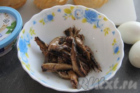 Теперь можно приготовить начинку. Шпроты без масла переложить в миску.