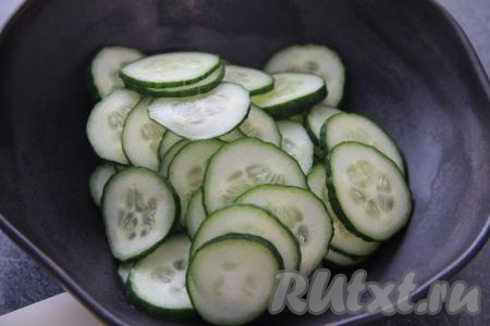 Огурчики нарезать на тонкие кружочки, выложить в салатник.