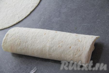 Завернуть тортилью с начинкой в виде шаурмы (то есть подвернуть ближнюю часть тортильи на начинку, а затем свернуть в рулет, начиная со стороны с начинкой, одну часть шаурмы я оставила открытой).