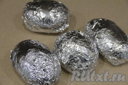 Завернуть каждую картошину в фольгу, переложить на противень и запекать в разогретой духовке при температуре 220 градусов минут 45. Время запекания зависит от сорта и размера клубней. Проверить готовность можно зубочисткой, проколов картофелину прямо через фольгу. Готовая картошка будет без усилий прокалываться зубочисткой.