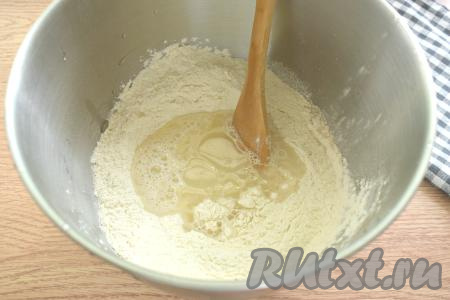 В центр смеси муки и дрожжей вливаем тёплую воду (её температура не должна быть выше 40 градусов) и растительное масло, перемешиваем тесто сначала лопаткой (или столовой ложкой).