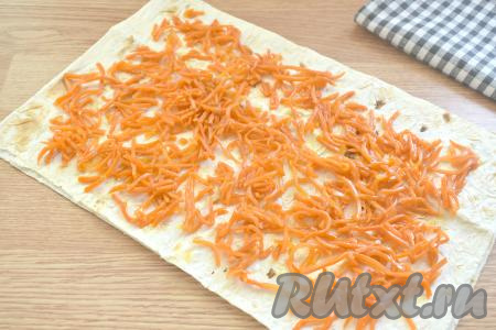 Лаваш, смазанный майонезом с сыром, накрываем второй частью лаваша. Распределяем по лавашу корейскую морковь, тоже немного отступив от краёв лаваша.