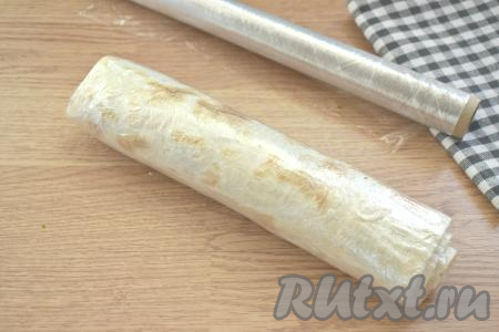 Заворачиваем сформированный рулет в пищевую плёнку и убираем в холодильник на 1-2 часа. Лаваш пропитается начинкой и станет более нежным и мягким.