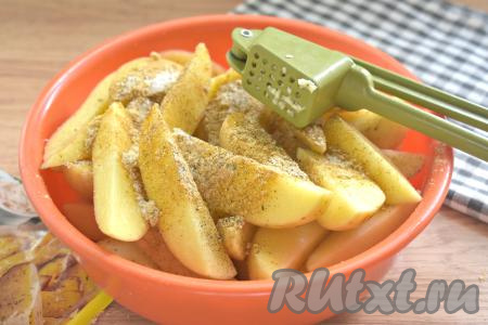 К долькам картошки добавляем приправу для блюд из картофеля, чёрный молотый перец, соль и пропущенный через пресс чеснок.