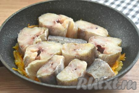 На обжаренные овощи выкладываем кусочки минтая в один слой.