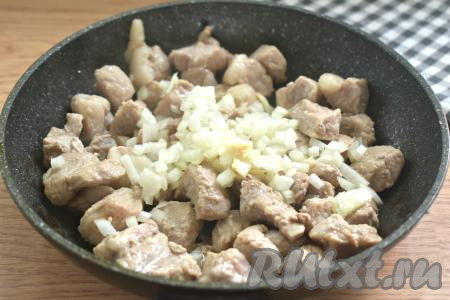 Нарезаем луковицу мелко, добавляем в сковороду к свинине, перемешиваем. Убавляем огонь до среднего и обжариваем мясо с луком, иногда помешивая, 5 минут.