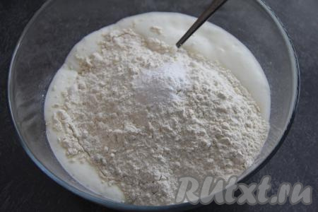 В миску с запенившейся кефирной смесью всыпать соль и сахар, добавить частями муку, каждый раз хорошо перемешивая. Замешиваем сначала бездрожжевое тесто ложкой, а затем хорошо вымешиваем его руками. Муку перестаём добавлять после того, как тесто перестанет липнуть к рукам, но при этом будет мягким, нежным.