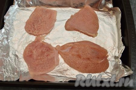 Застелить противень фольгой (или смазать растительным маслом, или застелить пергаментной бумагой), выложить отбитые кусочки куриного мяса, посолить филе, посыпать специями.