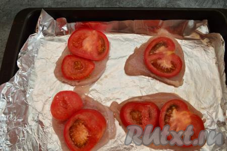 Помидор нарезать острым ножом на тонкие кружочки, выложить поверх мяса и присолить. Запекать куриное филе под помидорами в разогретой до 200 градусов духовке минут 10-15.