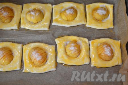 Желток отделить от белка. Взбить вилкой желток до однородности. Поверхность теста каждой слойки смазать взбитым желтком. 