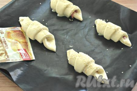 Круассаны смазываем взбитым яйцом и, по желанию, посыпаем кунжутом. Отправляем противень в разогретую до 200 градусов духовку.