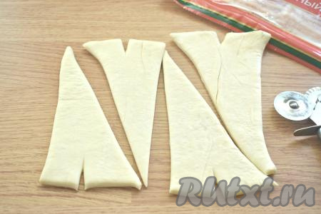 Теперь каждый прямоугольник разрезаем по диагонали. Из одного пласта теста получается 4 треугольных заготовки. У основания каждого треугольника делаем небольшой надрез, уголки немного разводим в стороны.