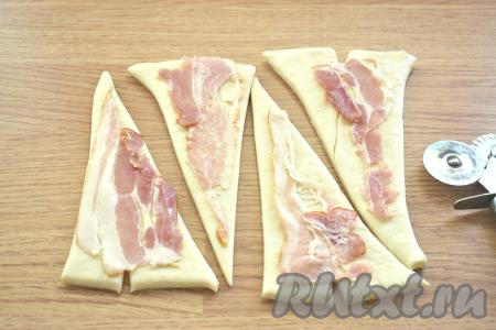 Полоски бекона разрезаем наискосок на 2 части и выкладываем на тесто, как на фото.
