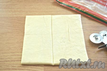 Рабочую поверхность слегка присыпаем мукой, выкладываем пласт слоёного теста, разрезаем его пополам (получаются прямоугольники). 
