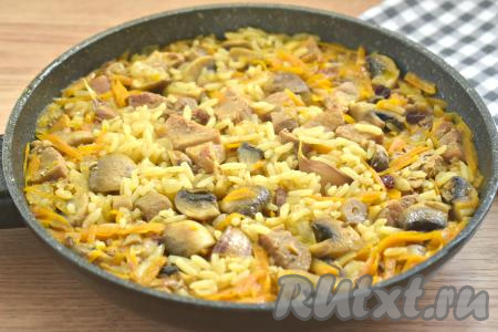 После закипания воды убавляем огонь, сковороду накрываем крышкой и готовим плов со свининой и шампиньонами 20-25 минут (до испарения жидкости).